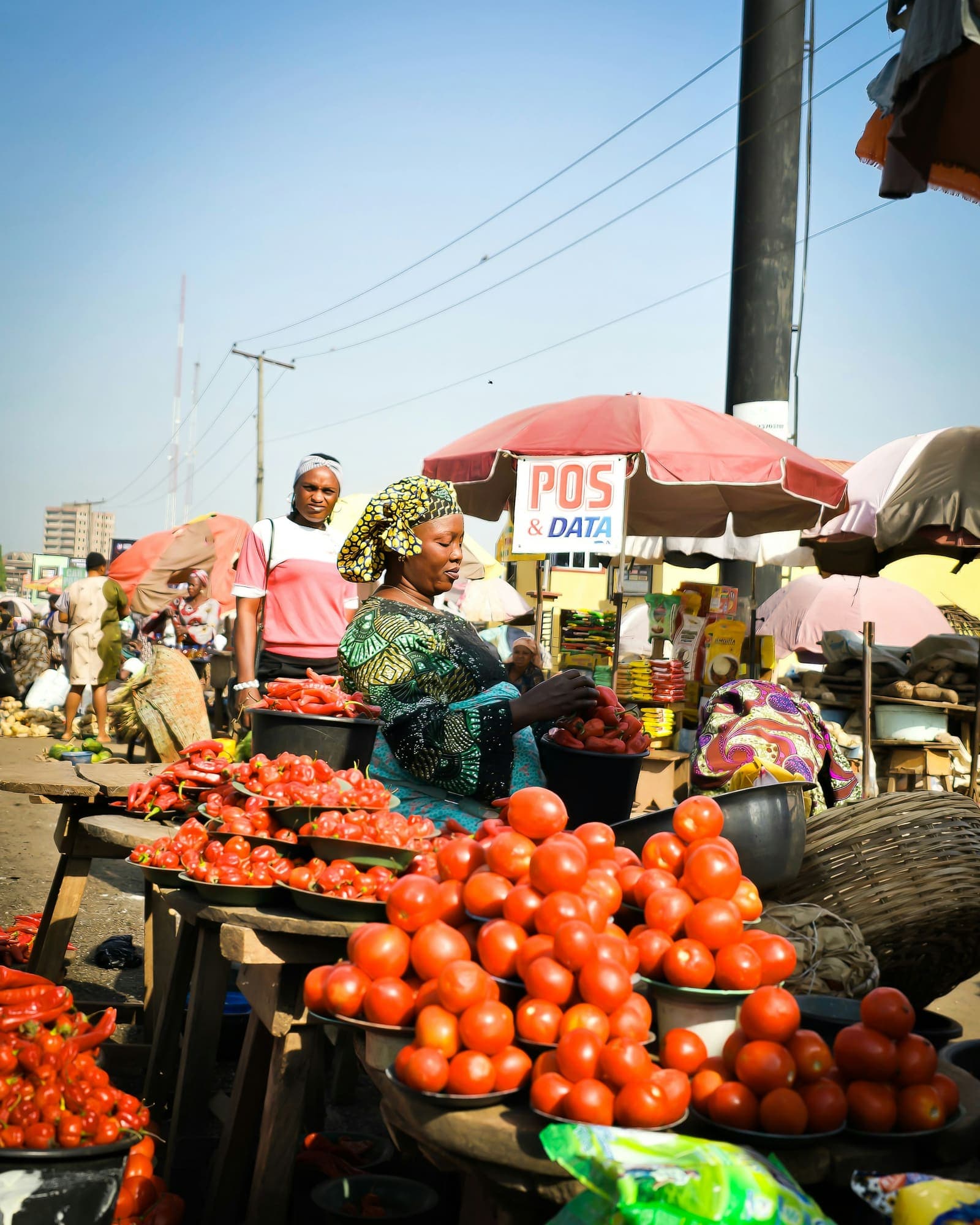 Des vendeuses de tomates sur un marché animé.