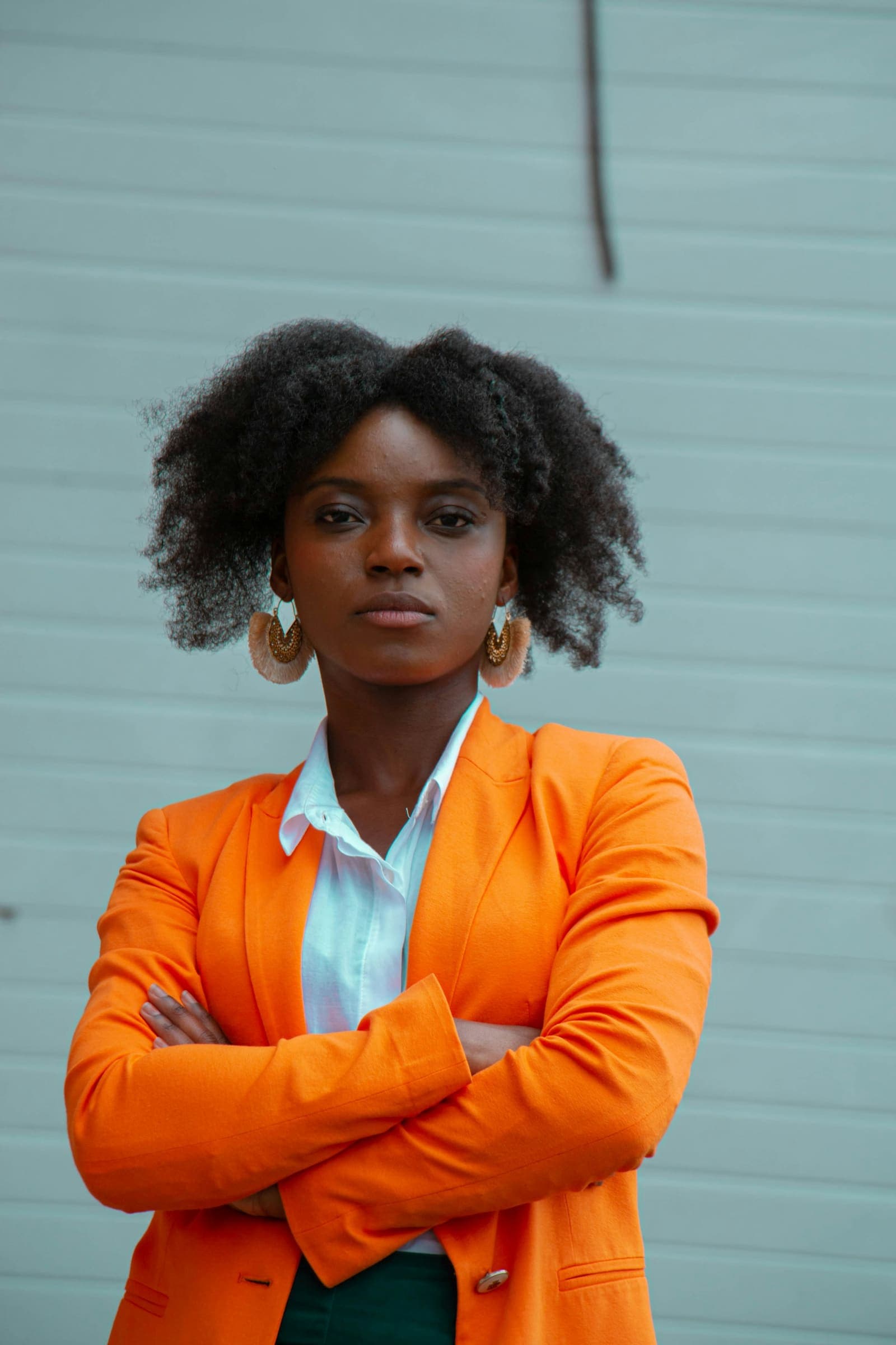 Une dirigeante en blazer orange, bras croisés, confiante.